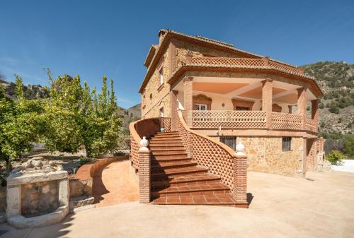 ein Backsteinhaus mit einer Treppe davor in der Unterkunft Casa Rural Villa la Gaviota con Piscina y Barbacoa junto a Ruta del Gollizno en Olivares in Olivares