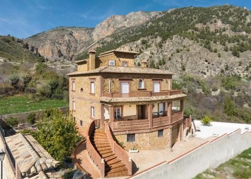 OlivaresにあるEscapada invernal, chimenea y barbacoa en Villa la Gaviota junto a Ruta del Gollizno en Olivaresの山を背景にした丘の上の古民家