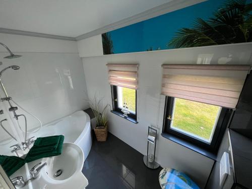 ein Bad mit einer Badewanne, einem Waschbecken und einem Fenster in der Unterkunft Banana Jack Boltenhagen in Boltenhagen