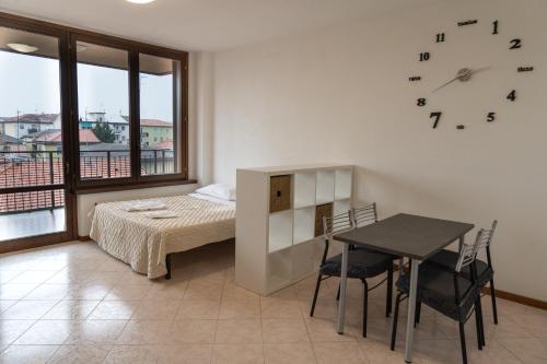 1 dormitorio con cama, mesa y reloj en Parcheggio Privato - Appartamento a Milano en Corsico