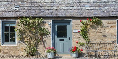 un cottage in pietra con porta blu e fiori in secchi di East End Cottage a Logierait