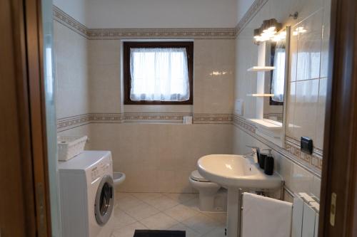 y baño con lavadora y lavamanos. en Parcheggio Privato - Appartamento a Milano en Corsico