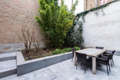 a patio with a table and chairs next to a brick wall at Dukes' Apartments Grand Place - by Dukes' Hotel Collection in Bruges