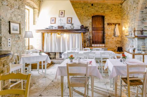 uma sala de jantar com mesas e cadeiras brancas em EcoResort Il Cantico della Natura em Magione