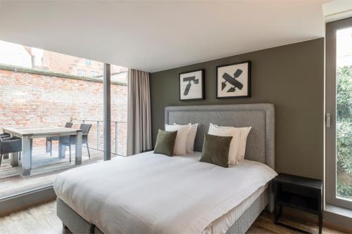 a bedroom with a large bed and a table at Dukes' Apartments Grand Place - by Dukes' Hotel Collection in Bruges