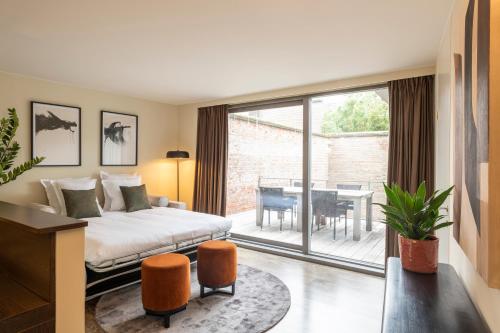 a bedroom with a bed and a balcony with a table at Dukes' Apartments Grand Place - by Dukes' Hotel Collection in Bruges
