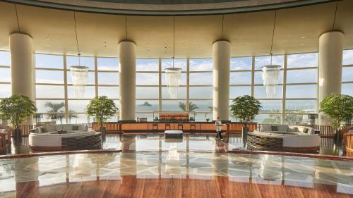 a large lobby with large windows and two people in the middle at Intercontinental Shenzhen Dameisha Resort by IHG in Shenzhen