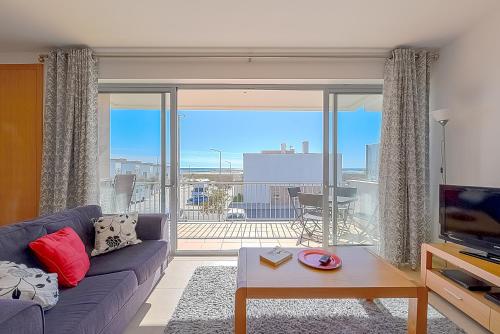 a living room with a couch and a large window at Apartamento Bonita - Fuseta in Fuzeta