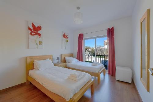 a bedroom with two beds and a window with pink curtains at Apartamento Bonita - Fuseta in Fuzeta