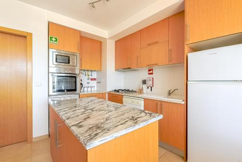 a kitchen with wooden cabinets and a marble counter top at Apartamento Bonita - Fuseta in Fuzeta