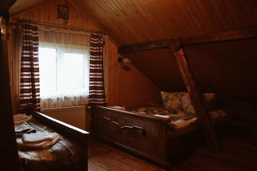 an attic room with a bed and a window at OSA - дерев'яні будиночки біля гірськолижного курорту in Tukholʼka