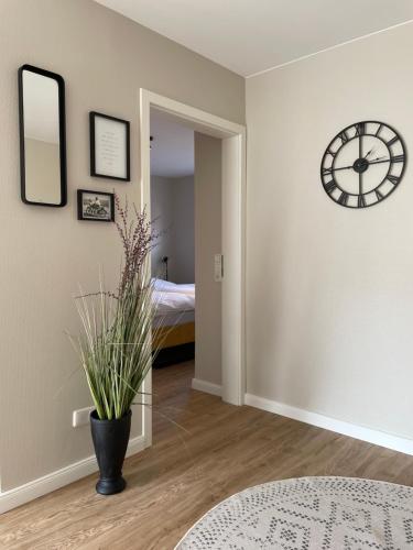 a room with a clock on the wall and a plant at Ferienwohnung Dünenbutze in Büsum