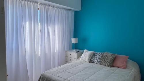 a bedroom with a bed with a blue wall at Bernardita in Ramos Mejía