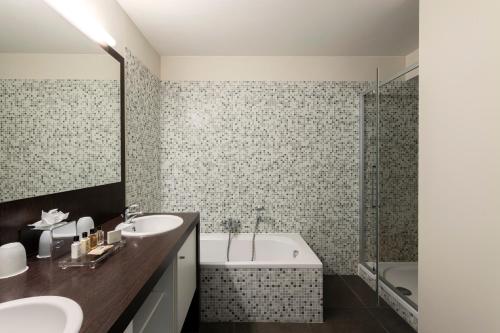 a bathroom with two sinks and a bath tub at Dukes' Apartments Grand Place - by Dukes' Hotel Collection in Bruges