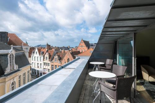a balcony with tables and chairs and a view of buildings at Dukes' Apartments Grand Place - by Dukes' Hotel Collection in Bruges