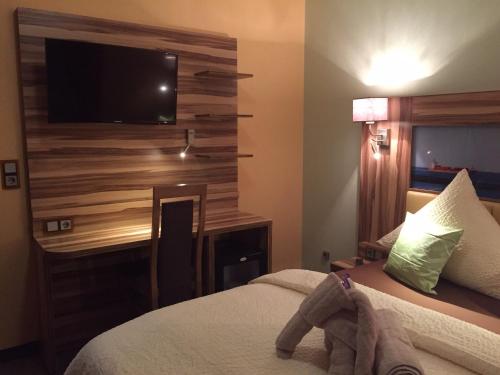 a hotel room with a bed and a television on a wall at Hotel Meereswoge in Cuxhaven