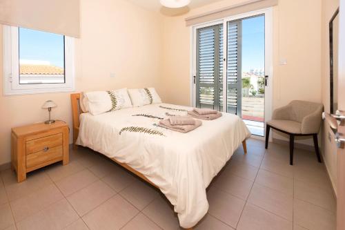 a bedroom with a bed and a chair and windows at Molly's Villa in Protaras