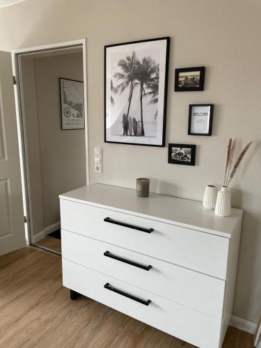 a white dresser in a room with pictures on the wall at Ferienwohnung Dünenbutze in Büsum