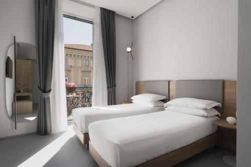 two beds in a hotel room with a window at The Grey in Naples