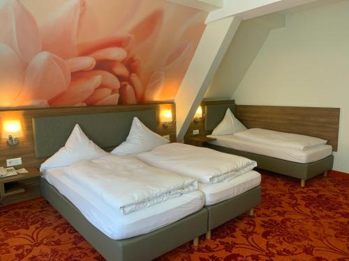 two beds in a room with a painting on the wall at Hotel Felsenkeller in Rüdesheim am Rhein