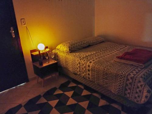 a bedroom with a bed and a table with a lamp at Suite aconchegante em Cruzeiro in Cruzeiro