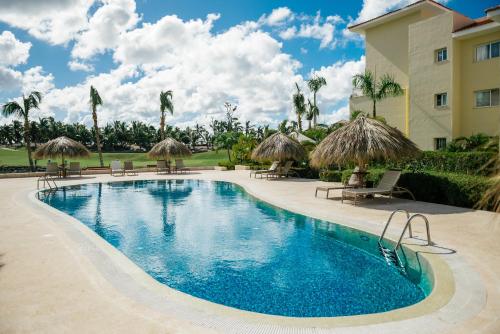 a swimming pool with chairs and umbrellas next to a building at Apartment Almas Iberosta Bavaro 3BDR with Pool and Private Beach in Punta Cana