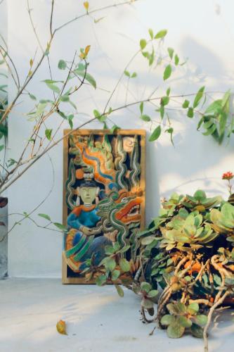 a painting on a wall next to a plant at Nhà Lúa Homestay in Ninh Binh