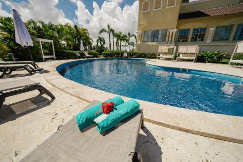 a swimming pool with a chaise lounge next to a house at Apartment Almas Iberosta Bavaro 3BDR with Pool and Private Beach in Punta Cana