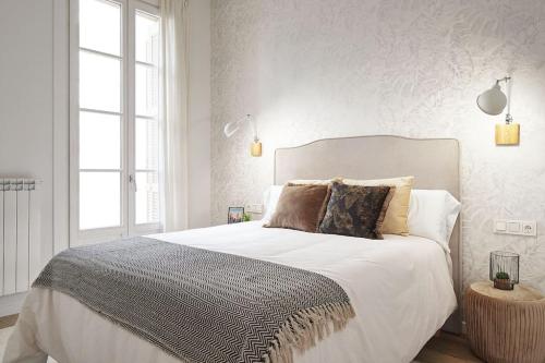 1 dormitorio con 1 cama grande con sábanas y almohadas blancas en NUEVO Apartamento en el centro de Donosti, en San Sebastián