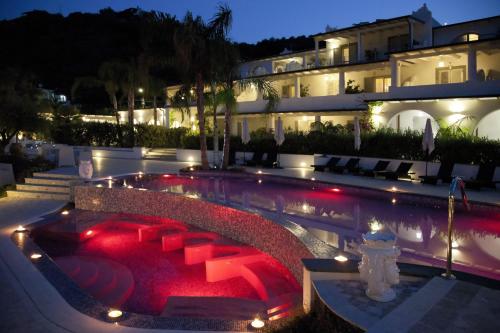 une piscine avec un hôtel en arrière-plan la nuit dans l'établissement Hotel Mea - Aeolian Charme, à Lipari