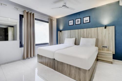 1 dormitorio con 1 cama grande y pared azul en Sleek Townhouse Galexia Hotel and Resorts, en Bangalore