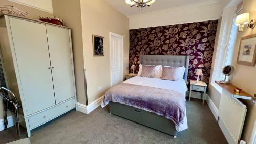 um quarto com uma cama com um edredão roxo em Tate House em Alnwick