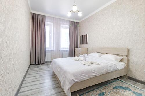 une chambre avec un grand lit avec des draps blancs dans l'établissement Жк Millennium Park,на Главной площади страны., à Astana