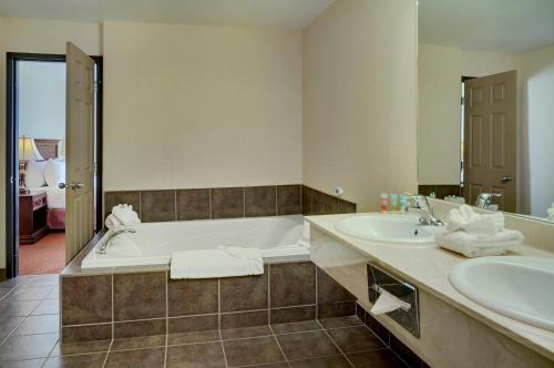 a bathroom with two sinks and a bath tub at Pomeroy Inn and Suites Chetwynd in Chetwynd