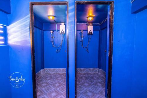 a bathroom with blue walls and two mirrors with lights at Time Sabai 32 in Bangkok