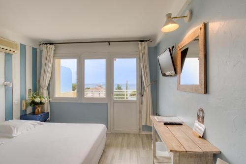 a bedroom with a bed and a desk and a window at Cap Nègre Hôtel in Le Lavandou