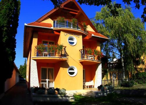 a yellow building with balconies and plants on it at Járja Panzió in Hajdúszoboszló