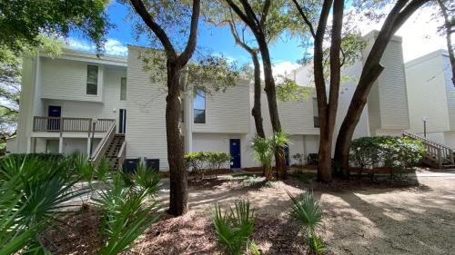 a white house with trees in front of it at Villas by The Sea Two Bedroom Apartment in Jekyll Island