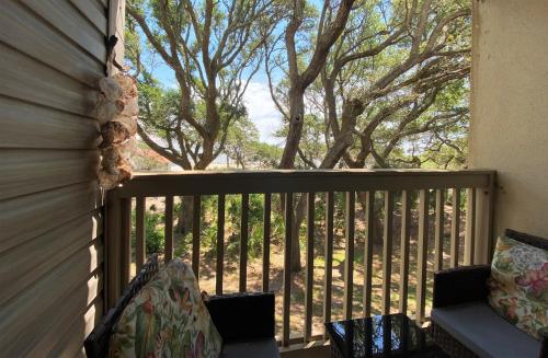 a screened in porch with a couch and trees at Villas by The Sea Two Bedroom Apartment in Jekyll Island