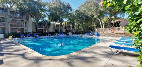a swimming pool with blue chairs and a resort at Villas by The Sea Two Bedroom Apartment in Jekyll Island