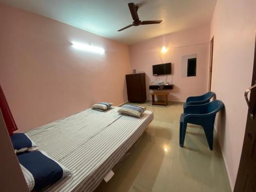 Cette chambre comprend un lit et une chaise bleue. dans l'établissement Family Guest House Pondicherry, à Vānūr