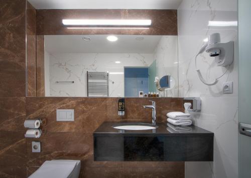 bagno con lavandino, servizi igienici e specchio di Hotel Essence a Praga