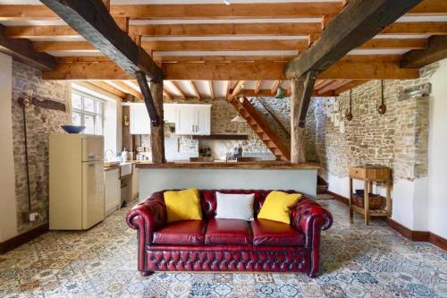 a red couch with yellow pillows in a kitchen at Glatigny Farmhouse - close to beach - proche de la plage in Glatigny