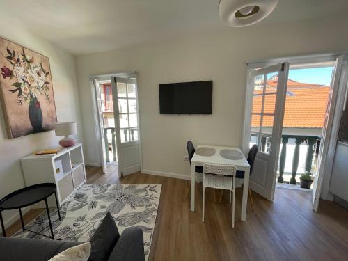 a living room with a table and a tv on the wall at RETIRO 402 in Guimarães