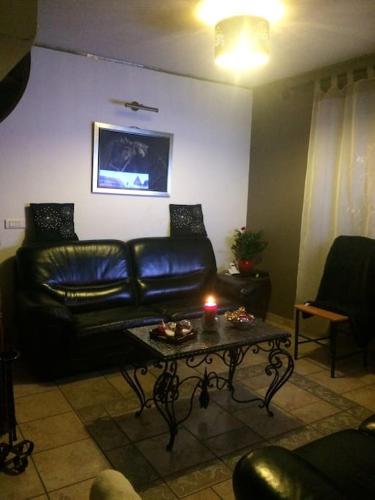 a living room with a leather couch and a table with a candle at Gîte Le Faucon in Thilay