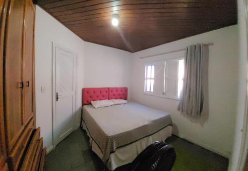um pequeno quarto com uma cama e uma janela em Casa de praia / piscina em Santa Cruz Cabrália