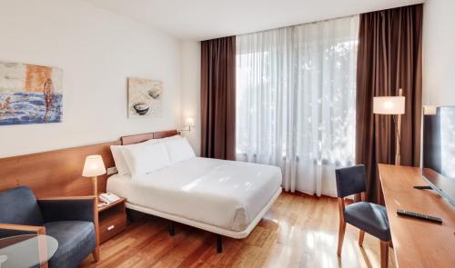 a hotel room with a bed and a desk at Sercotel Arrahona Sabadell in Sabadell