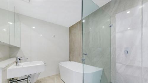 a white bathroom with a sink and a shower at Comfort Living - 3 Bedroom sleeps 6 , parking, pool, other amenities - Near Showgrounds, NO PARTIES in Sydney