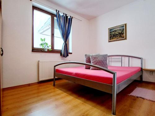 - une chambre avec un lit doté d'une couverture rouge et d'une fenêtre dans l'établissement Apartmán Severanka, à Vysoké Tatry