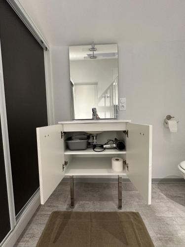 a white cabinet with a mirror in a bathroom at L'Entrepotes in Rethel